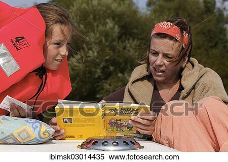 "Mother and daughter reading a children's book, """"Die wilden Huhner"""", German for """"The Wild Chicks"""" on a houseboat on the Saone River, Cendrecourt, Vesoul, Region Franche-Comte, Dep. Haute-Saone, France, Europe" View Large Photo Image Stock Photography - "Mother and daughter reading a children's book, """"Die wilden Huhner"""", German for """"The Wild Chicks"""" on a houseboat on the Saone River, Cendrecourt, Vesoul, Region Franche-Comte, Dep. Haute-Saone, France, Europe". Fotosearch