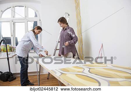 "Mother and daughter renovating a room, preparing wallpaper for wallpapering the walls" View Large Photo Image Stock Image - "Mother and daughter renovating a room, preparing wallpaper for wallpapering the walls". Fotosearch