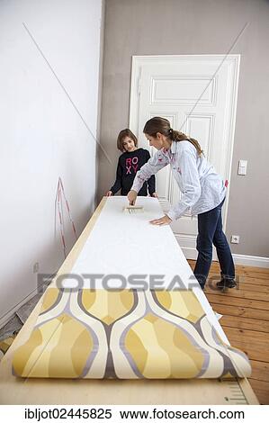 "Mother and daughter renovating a room, preparing wallpaper for wallpapering a wall" View Large Photo Image Stock Photography - "Mother and daughter renovating a room, preparing wallpaper for wallpapering a wall". Fotosearch