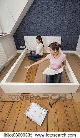 Stock Photography - "Mother and daughter working together to assemble a bed in the daughter's room, bed assembly set, Germany, Europe". Fotosearch