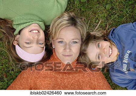 Mother and daughters lying head to head on the grass View Large Photo Image Stock Image - Mother and daughters lying head to head on the grass. Fotosearch