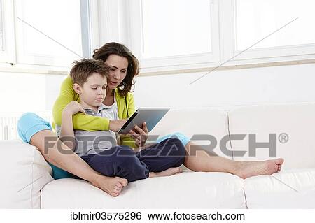Stock Photograph - "Mother and son using a tablet pc on a sofa, Germany, Europe". Fotosearch