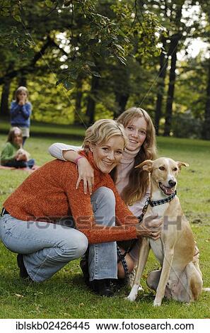 Stock Photography - Mother and three daughters with a dog in a park. Fotosearch