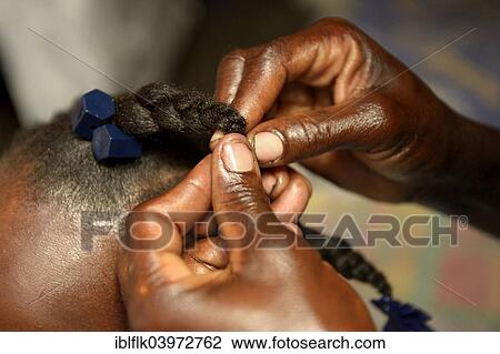 Stock Image - "Mother braiding her daughter's hair, Camp Icare, camp for earthquake refugees, Fort National, Port-au-Prince, Haiti, North America". Fotosearch