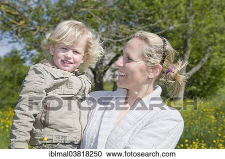 Stock Image - Mother holding her son in her arms on a spring meadow. Fotosearch