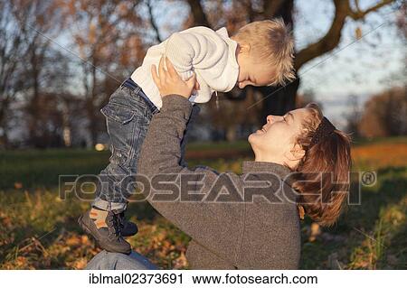 Mother playing with her two-year-old son in the autumn park View Large Photo Image Stock Image - Mother playing with her two-year-old son in the autumn park. Fotosearch