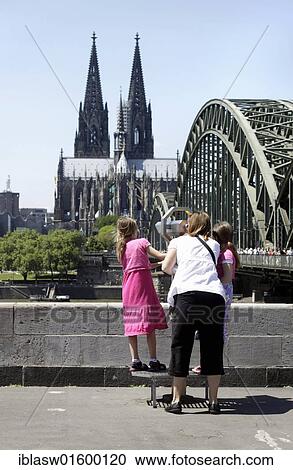 Stock Image - "Mother with two children looking at the cathedral through binoculars, Cologne, North Rhine-Westphalia, Germany, Europe". Fotosearch