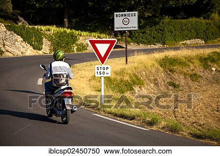 Stock Image - "Motocyclist on country road in Provence, France, Europe". Fotosearch