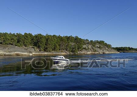 Picture - "Motorboat off the island of Soder Langjolm, viewed from Finnhamn Island, Stockholm Middle Archipelago, Stockholm, Sweden, Europe". Fotosearch