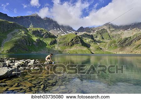 "Mountaineer filling a water bottle at Grosser Schwarzsee Lake or Lago Nero, Mount Schwarzwandspitze at back, Stubai Alps, South Tyrol province, Trentino-Alto Adige, Italy, Europe" View Large Photo Image Stock Image - "Mountaineer filling a water bottle at Grosser Schwarzsee Lake or Lago Nero, Mount Schwarzwandspitze at back, Stubai Alps, South Tyrol province, Trentino-Alto Adige, Italy, Europe". Fotosearch