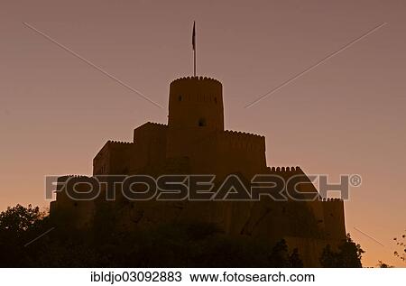 Stock Image - "Nakhal Fort or Nakhl Fort back-lit by the setting sun, Nakhal, Al Batinah, Oman, Asia". Fotosearch