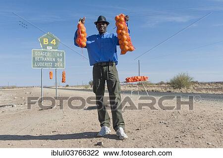 Stock Image - "Namibian man selling oranges along the B4 road, Namibia, Africa". Fotosearch
