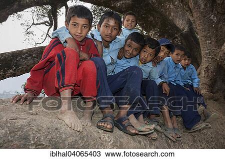 Stock Image - "Nepalese students wearing school uniforms sitting on a tree, Bandipur, Nepal, Asia". Fotosearch