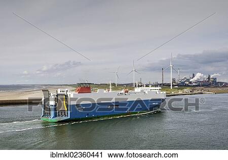 Stock Image - "Nordic Ace car ferry approaching the port of Ijmuiden, wind turbines and industrial facilities at the back, North Holland, the Netherlands, Europe". Fotosearch