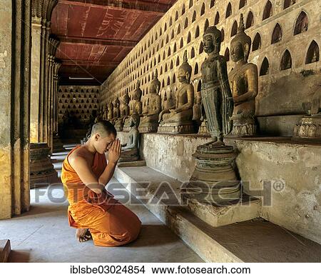 "Novice praying in front of a bronze Buddha, walkway in the courtyard of Wat Si Saket Temple, lined with ancient statues of Buddha, Vientiane, Vientiane Province, Laos, Asia" View Large Photo Image Picture - "Novice praying in front of a bronze Buddha, walkway in the courtyard of Wat Si Saket Temple, lined with ancient statues of Buddha, Vientiane, Vientiane Province, Laos, Asia". Fotosearch