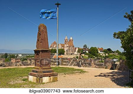 Stock Image - "Obelisk and the European flag on Eckartsberg hill in front of the historic centre of Breisach with St. Stephansmunster Cathedral, Breisach, Baden-Wurttemberg, Germany, Europe". Fotosearch