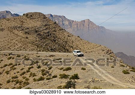 Stock Image - "Off-road vehicle on a track in the rugged mountain landscape at the Sharaf al Alamayn Pass, Oman, Asia". Fotosearch