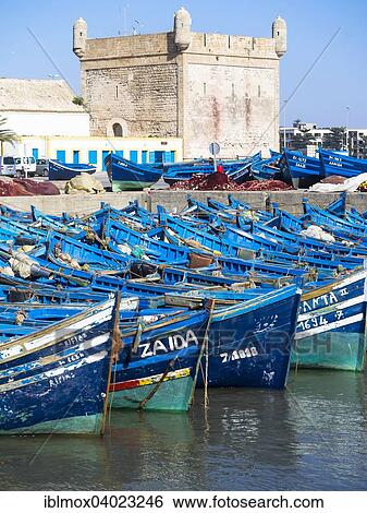 Stock Photograph - "Old blue fishing boats in the port of Essaouira, behind the fortress of Essaouira, Unesco World Heritage Site, Morocco, Africa". Fotosearch