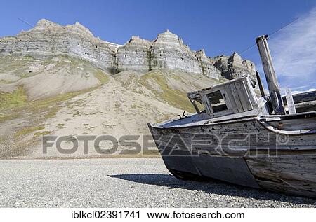 Stock Image - "Old boat, probably built in 1918, on the beach below the bird cliffs of Skansen in Skansbukta, Billefjorden, Isfjorden, Spitsbergen, Svalbard, Norway, Europe". Fotosearch