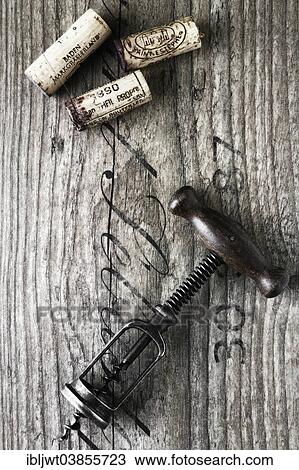 Stock Image - Old corkscrew with wine corks on a wooden board. Fotosearch