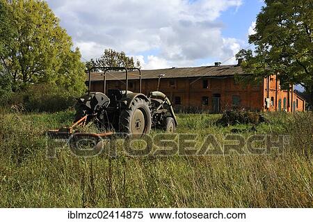 Stock Photography - Old Fendt tractor from 1969 on a meadow, behind a pigsty from 1920, Gut Othenstorf, Zum Weissen Haus, Mecklenburg-Western Pomerania, Germany, Europe. Fotosearch