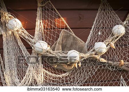 Stock Image - "Old fishing net hanging on a wooden wall, Germany, Europe". Fotosearch