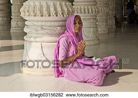 Stock Image - "Old Indian woman in a sari sitting on the floor in prayer, in front of an ornate marble column, at Shri Swaminarayan Mandir, a Hindu temple of the Swaminarayana sect, Bhuj, Gujarat, India, Asia". Fotosearch