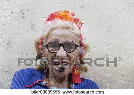 Stock Photograph - "Old woman wearing coulorful clothes posing with a cigar, Havana, Cuba, North America". Fotosearch