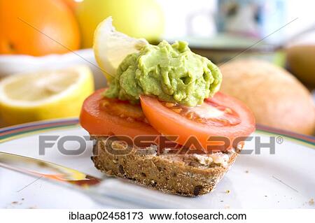 Stock Image - Organic wholemeal bun with a tomato and guacamole. Fotosearch