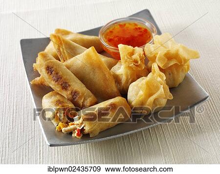 Stock Photo - "Oriental selection with dim sum, spring rolls with chicken and vegetables and vegetable samosas with a chilli dipping sauce". Fotosearch
