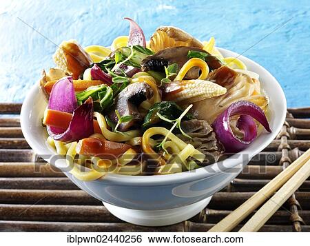 Stock Photograph - "Oriental vegetarian stir fry of vegetables, noodles and mushrooms in a bowl with chop sticks". Fotosearch