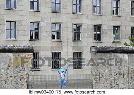 "Original remains of the Berlin Wall in Niederkirchnerstrasse street, Detlev Rohwedder Building, Ministry of Finance, with a Charl Buddy Bear at back, Berlin, Berlin, Germany, Europe" View Large Photo Image Stock Photography - "Original remains of the Berlin Wall in Niederkirchnerstrasse street, Detlev Rohwedder Building, Ministry of Finance, with a Charl Buddy Bear at back, Berlin, Berlin, Germany, Europe". Fotosearch