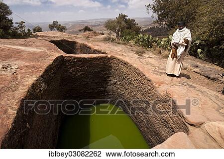 Stock Image - "Orthodox monks at the holy water near the rock-hewn church of Mikael Imba, Felsenkirche Mikael Imba, Atzbi, Tigray, Ethiopia, Africa". Fotosearch