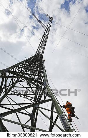 "Overhead transmission cable installer climbing a mast to install insulated cable on a newly built high-voltage transmission mast, Monchenholzhausen, Thuringia, Germany, Europe" View Large Photo Image Stock Image - "Overhead transmission cable installer climbing a mast to install insulated cable on a newly built high-voltage transmission mast, Monchenholzhausen, Thuringia, Germany, Europe". Fotosearch