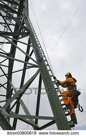 "Overhead transmission cable installer climbing a mast to install insulated cable on a newly built high-voltage transmission mast, Monchenholzhausen, Thuringia, Germany, Europe" View Large Photo Image Stock Photo - "Overhead transmission cable installer climbing a mast to install insulated cable on a newly built high-voltage transmission mast, Monchenholzhausen, Thuringia, Germany, Europe". Fotosearch