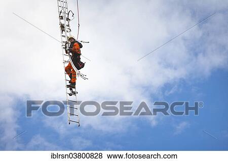 "Overhead transmission cable installer installing insulated cable on the cross arm of a newly built high-voltage transmission mast, Monchenholzhausen, Thuringia, Germany, Europe" View Large Photo Image Stock Photo - "Overhead transmission cable installer installing insulated cable on the cross arm of a newly built high-voltage transmission mast, Monchenholzhausen, Thuringia, Germany, Europe". Fotosearch