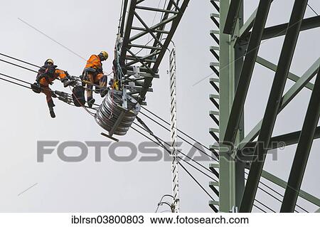"Overhead transmission cable installers installing insulated cable on the cross arm of a newly built high-voltage transmission mast, Monchenholzhausen, Thuringia, Germany, Europe" View Large Photo Image Stock Image - "Overhead transmission cable installers installing insulated cable on the cross arm of a newly built high-voltage transmission mast, Monchenholzhausen, Thuringia, Germany, Europe". Fotosearch