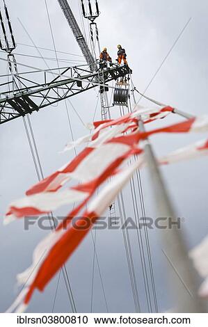 "Overhead transmission cable installers installing insulated cable on the cross arm of a newly built high-voltage transmission mast, Monchenholzhausen, Thuringia, Germany, Europe" View Large Photo Image Stock Image - "Overhead transmission cable installers installing insulated cable on the cross arm of a newly built high-voltage transmission mast, Monchenholzhausen, Thuringia, Germany, Europe". Fotosearch