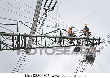 "Overhead transmission cable installers installing insulated cable on the cross arm of a newly built high-voltage transmission mast, Monchenholzhausen, Thuringia, Germany, Europe" View Large Photo Image Stock Photo - "Overhead transmission cable installers installing insulated cable on the cross arm of a newly built high-voltage transmission mast, Monchenholzhausen, Thuringia, Germany, Europe". Fotosearch