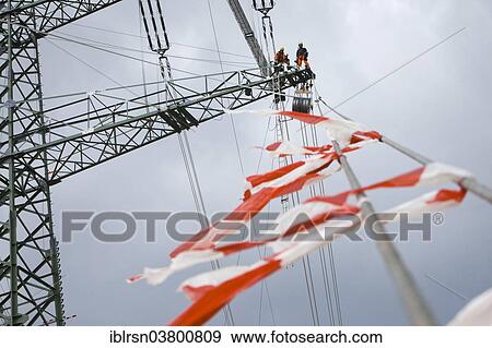 "Overhead transmission cable installers installing insulated cable on the cross arm of a newly built high-voltage transmission mast, Monchenholzhausen, Thuringia, Germany, Europe" View Large Photo Image Stock Photo - "Overhead transmission cable installers installing insulated cable on the cross arm of a newly built high-voltage transmission mast, Monchenholzhausen, Thuringia, Germany, Europe". Fotosearch