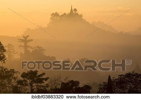 Stock Image - "Pagoda surrounded by trees, in the mist, in the morning light, Mrauk U, Sittwe District, Rakhine State, Myanmar, Asia". Fotosearch
