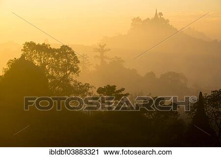 Stock Image - "Pagoda surrounded by trees, in the mist, in the morning light, Mrauk U, Sittwe District, Rakhine State, Myanmar, Asia". Fotosearch