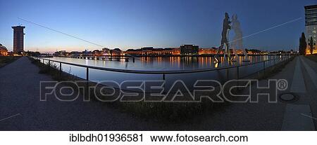Stock Image - "Panoramic view, twilight at the Osthafen harbour, Molecule Men sculpture, Friedrichshain, Treptow, Kreuzberg, Berlin, Germany, Europe". Fotosearch