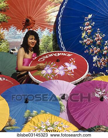 Stock Image - "Parasol painting, young woman painting silk parasols, Bo Sang, Chiang Mai, Northern Thailand, Thailand, Asia". Fotosearch