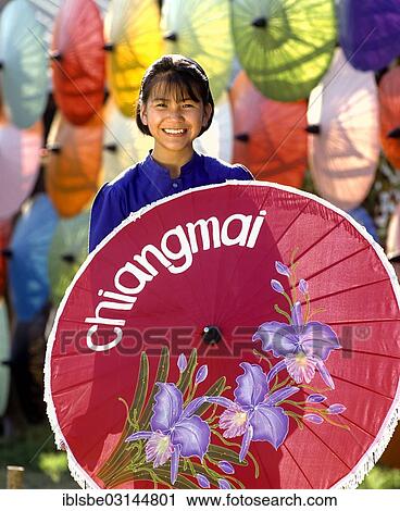 Stock Image - "Parasol painting, young woman with silk parasols, Bo Sang, Chiang Mai, Northern Thailand, Thailand, Asia". Fotosearch