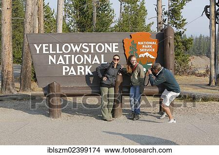 "Participants of the Old Faithful Yellowstone tour, at the entrance sign to Yellowstone National Park, Wyoming, USA" View Large Photo Image Picture - "Participants of the Old Faithful Yellowstone tour, at the entrance sign to Yellowstone National Park, Wyoming, USA". Fotosearch