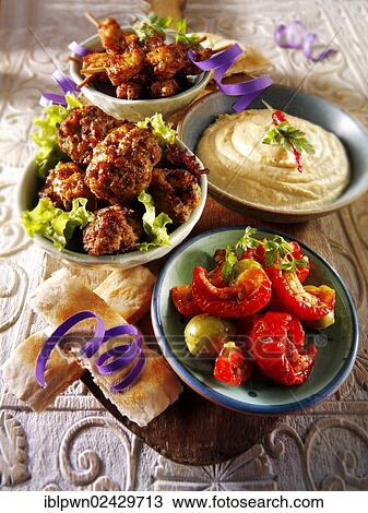 Stock Image - "Party buffet food with Hummus, meatballs, chicken satay and sundried tomatoes". Fotosearch