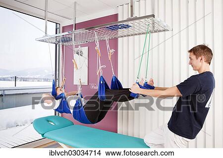 Patient and physiotherapist during sling table therapy View Large Photo Image Picture - Patient and physiotherapist during sling table therapy. Fotosearch