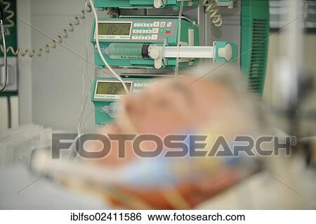 Stock Photograph - Patient in an ICU, intensive care unit, with a syringe pump or dosing pump for intravenous administration of drugs, hospital, Germany, Europe. Fotosearch