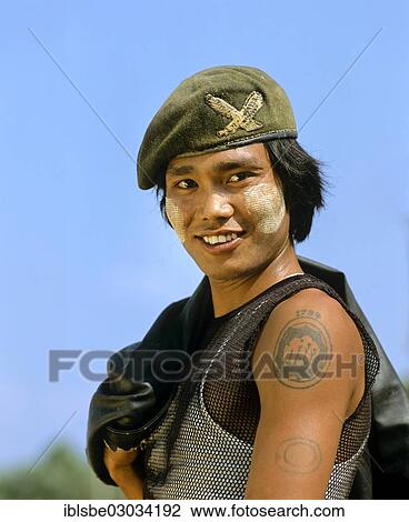 Stock Image - "Patriotic young man with thanaka paste on his face, wearing an army cap and a leather jacket, Tachilek, Shan State, Myanmar, Burma, Asia". Fotosearch